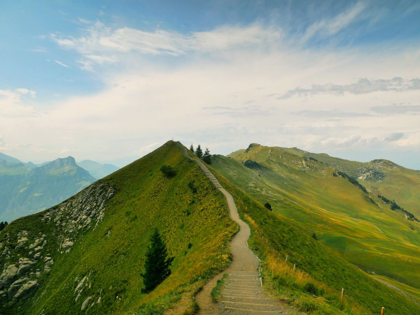 Mountain path winding through green hills under an open sky
